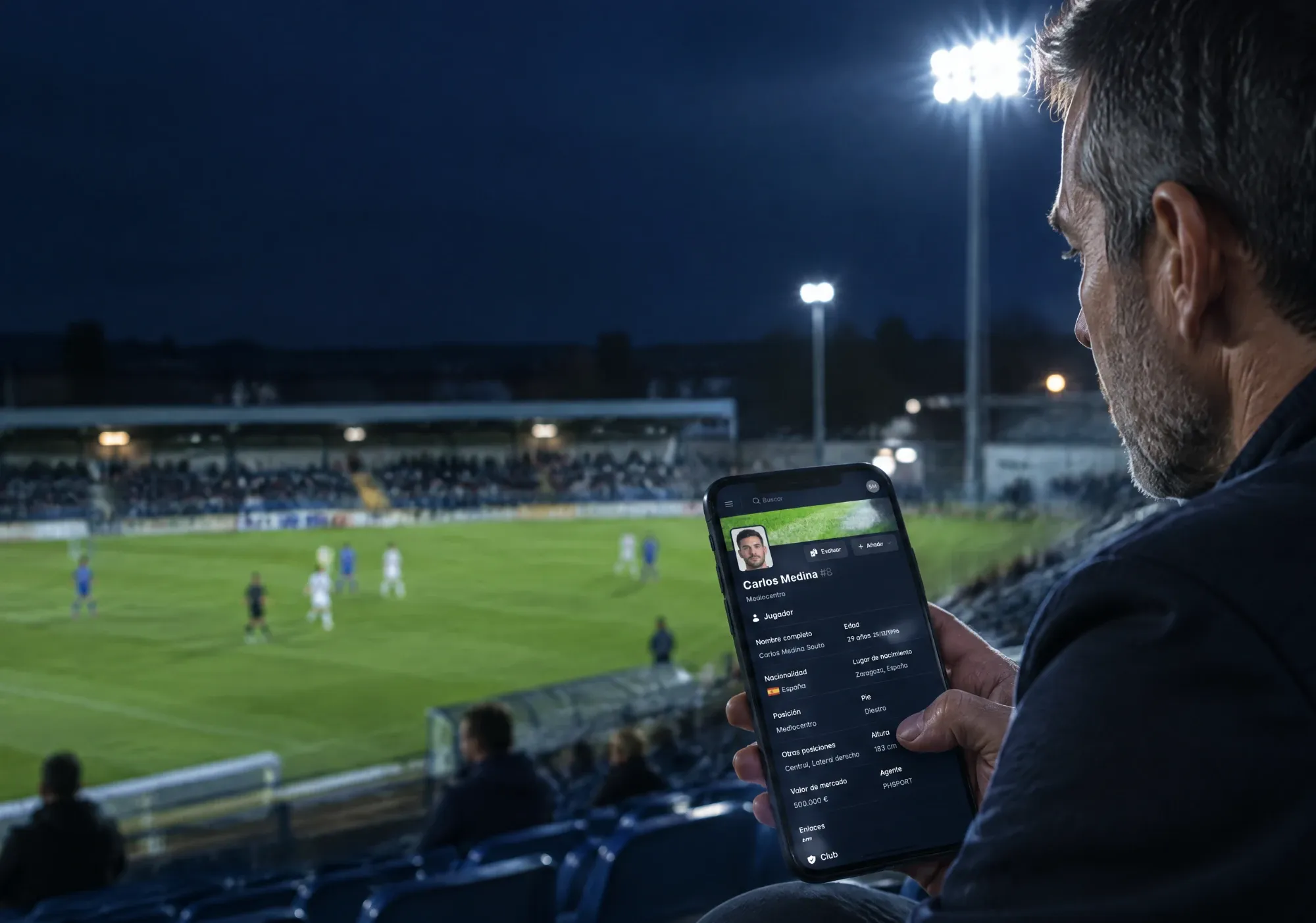 Scout in a stadium at night checking a player profile on the Sunday Metrics app